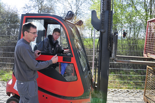Junge in Stapler hört Anleiter zu und fährt